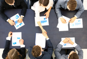 Business people handshake, businessmen hand shake, during meeting signing agreement sitting at desk team work group on conference discussing financial diagram, graph, business charts, top angle view
